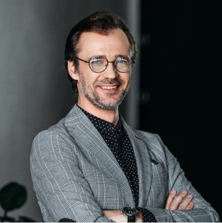 Professional man in glasses and gray blazer smiling confidently.