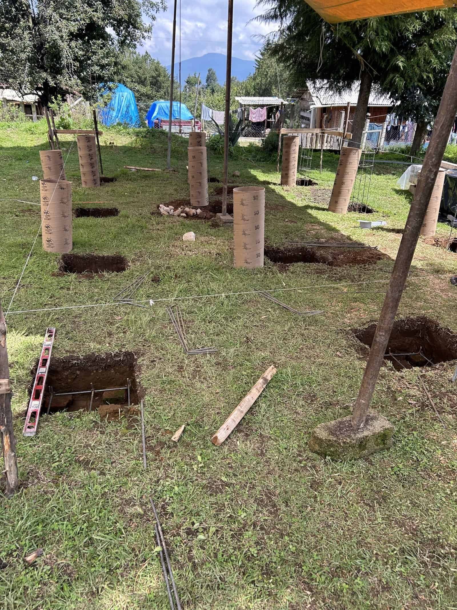 Construction site showing foundation holes and wooden formwork for residential buildings.