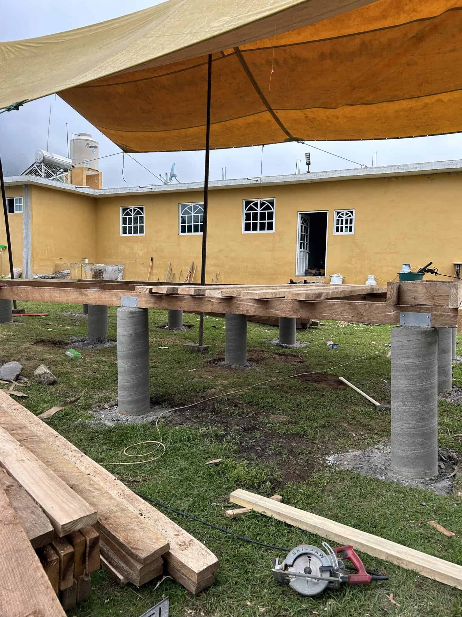 Construction site with concrete pillars and wooden beams for building foundation.